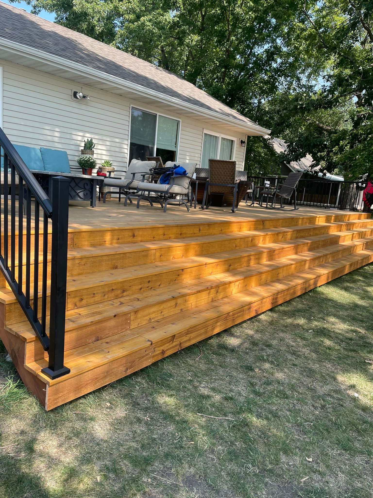 Beautiful wooden deck with black railings and outdoor furniture
